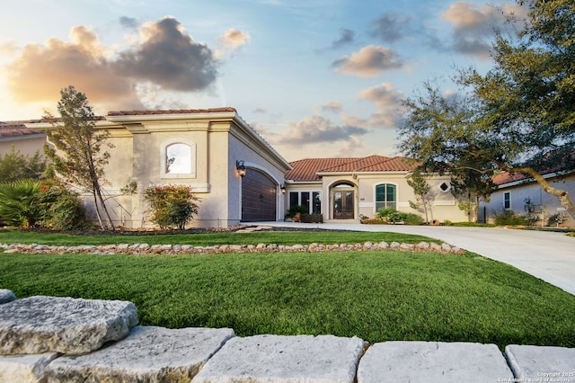 mediterranean / spanish home featuring concrete driveway, a yard, and a tile roof