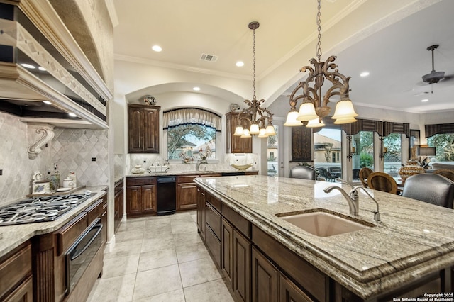 kitchen featuring visible vents, a large island, light stone counters, premium range hood, and a sink