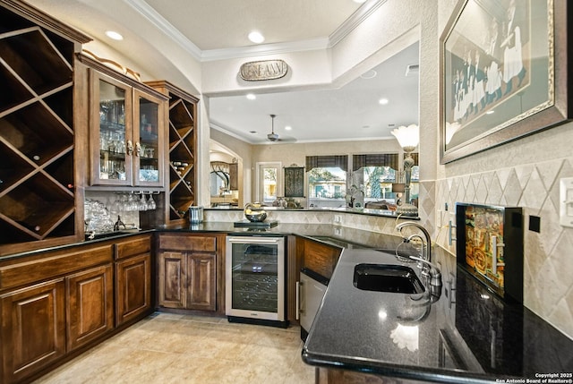 kitchen with wine cooler, a peninsula, a sink, ornamental molding, and glass insert cabinets