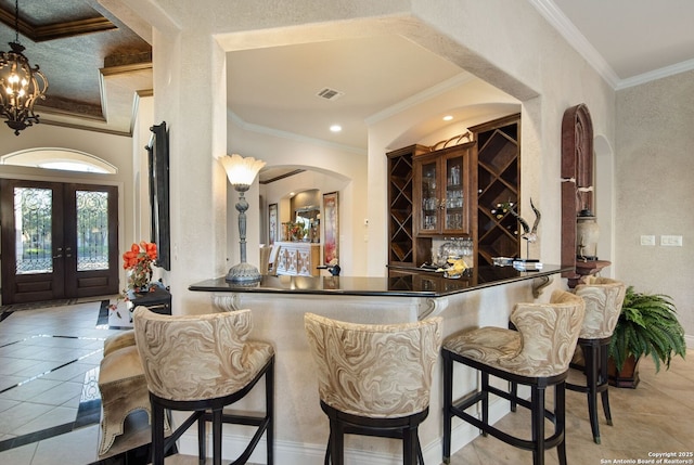 bar featuring visible vents, arched walkways, crown molding, and light tile patterned flooring