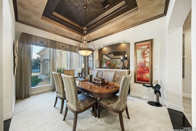 dining room featuring ornamental molding, a tray ceiling, visible vents, and baseboards