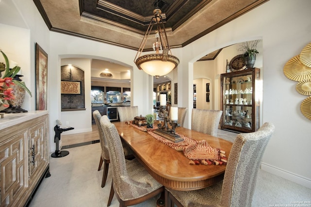 dining area with baseboards, arched walkways, a raised ceiling, and crown molding