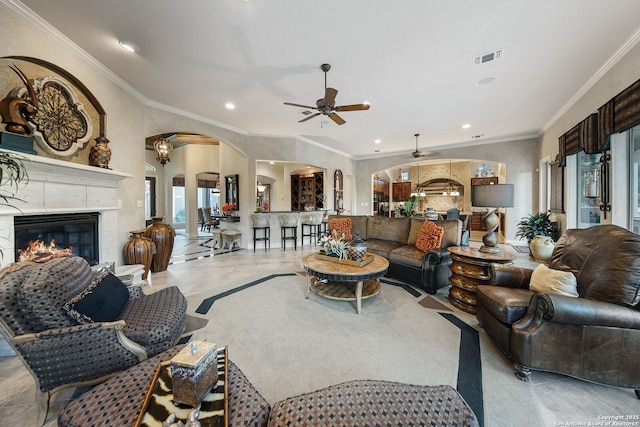 living area with arched walkways, visible vents, ceiling fan, a premium fireplace, and recessed lighting