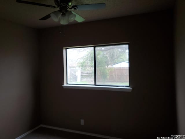 unfurnished room with ceiling fan and baseboards