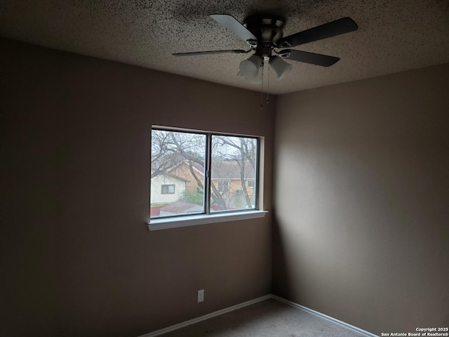 carpeted empty room featuring a ceiling fan, a textured ceiling, and baseboards