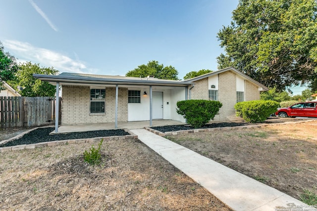 single story home with covered porch, brick siding, and fence