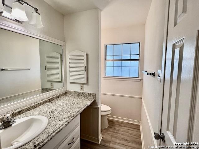 bathroom with toilet, baseboards, wood finished floors, and vanity