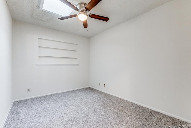 carpeted empty room with built in features, a textured ceiling, baseboards, and a ceiling fan