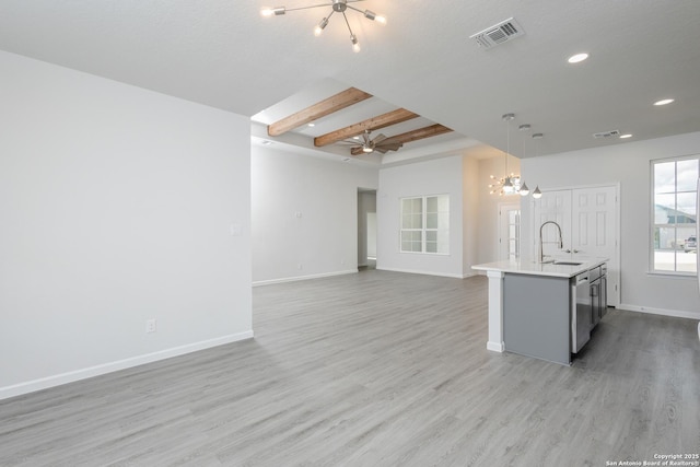 kitchen with open floor plan, light countertops, a center island with sink, and decorative light fixtures