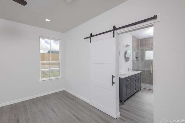 full bathroom with a tile shower, plenty of natural light, wood finished floors, and baseboards