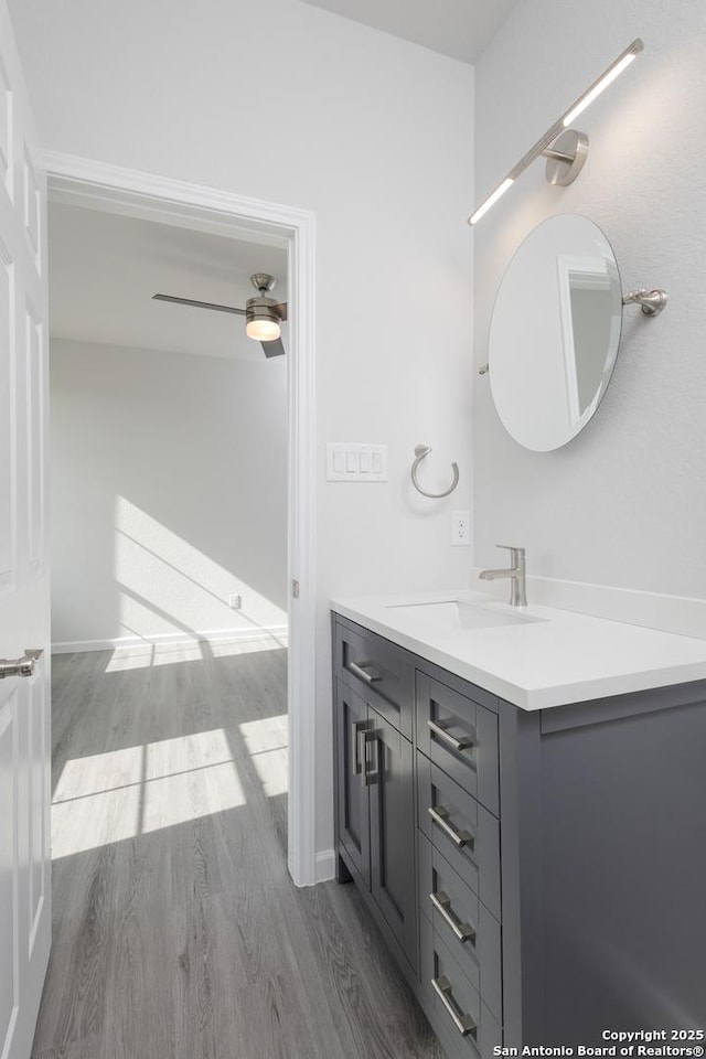 bathroom with ceiling fan, wood finished floors, and vanity