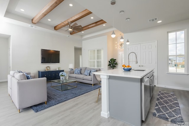 kitchen featuring pendant lighting, light countertops, open floor plan, and a kitchen island with sink