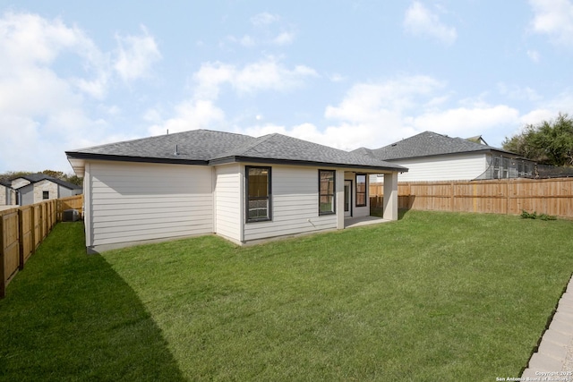 rear view of property featuring a fenced backyard, a yard, a patio, and roof with shingles