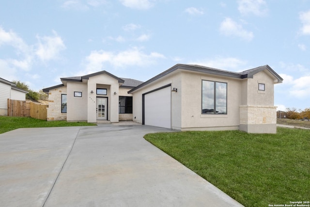 view of front of home with a garage, driveway, fence, a front yard, and stucco siding