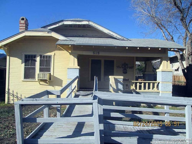 view of front of home featuring a chimney and a porch