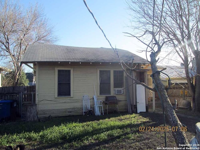 back of property with a shingled roof and fence