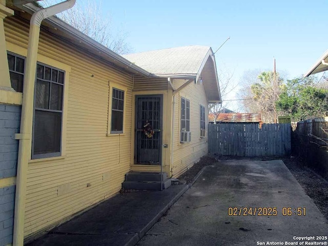 view of home's exterior with entry steps, fence, cooling unit, and a patio