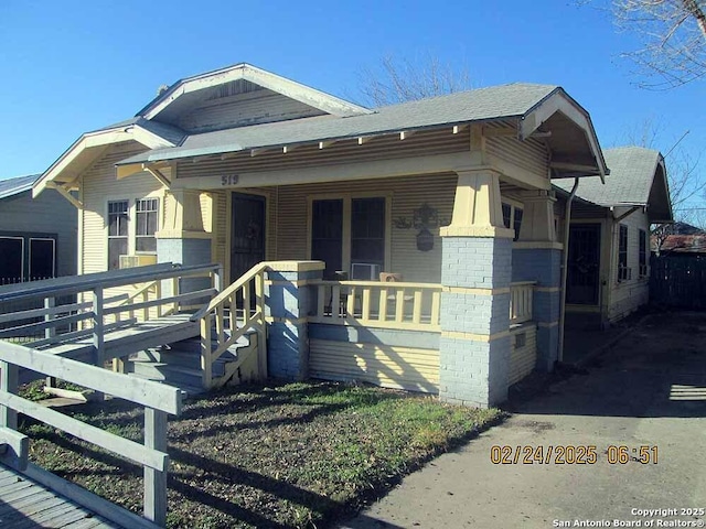 view of front of home featuring covered porch, roof with shingles, and brick siding