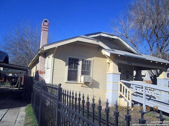 view of home's exterior with covered porch, a chimney, and a fenced front yard