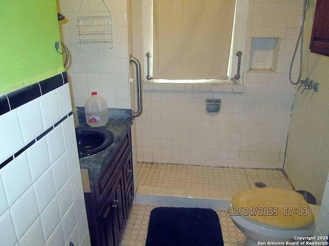 bathroom with toilet, a shower stall, tile walls, and vanity