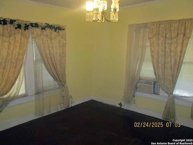 spare room featuring an inviting chandelier, cooling unit, baseboards, and crown molding