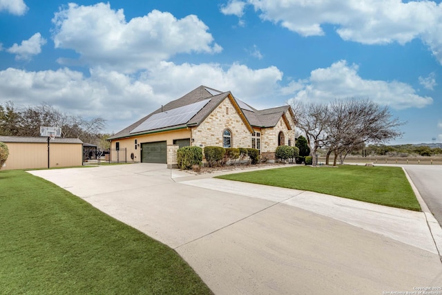 view of front facade with stone siding, a front yard, roof mounted solar panels, and driveway