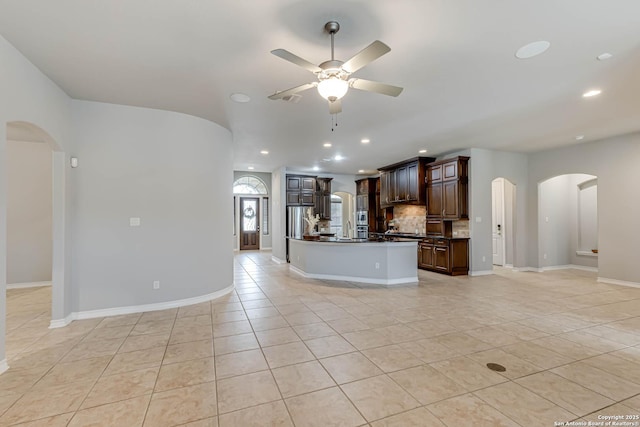 kitchen featuring a ceiling fan, dark countertops, arched walkways, and dark brown cabinets