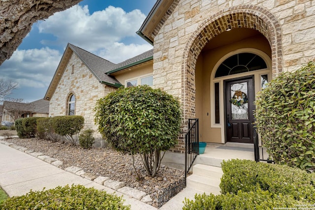 view of exterior entry featuring a shingled roof