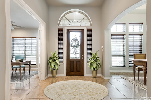 foyer with a healthy amount of sunlight, light tile patterned floors, and arched walkways