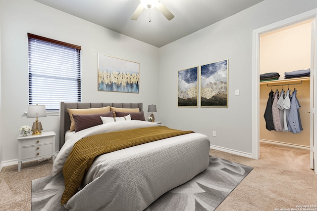 bedroom featuring baseboards, light colored carpet, ceiling fan, a walk in closet, and a closet