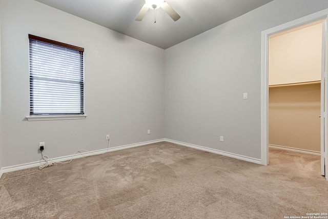 spare room featuring a ceiling fan, light carpet, and baseboards