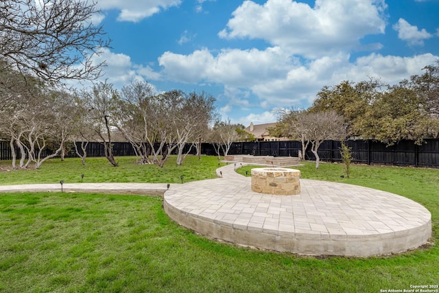 view of community featuring a patio area, a fenced backyard, a yard, and a fire pit