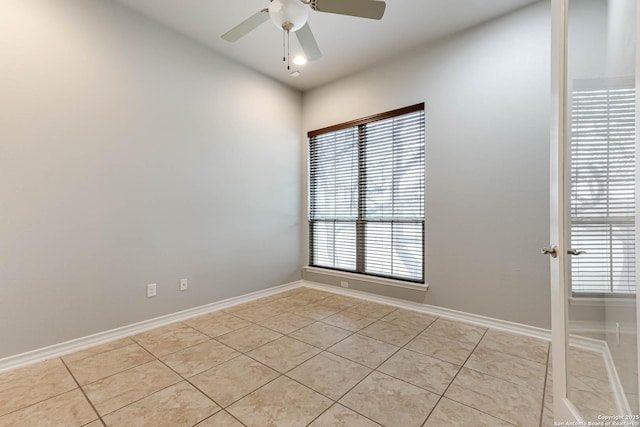 empty room with light tile patterned floors, baseboards, and a ceiling fan