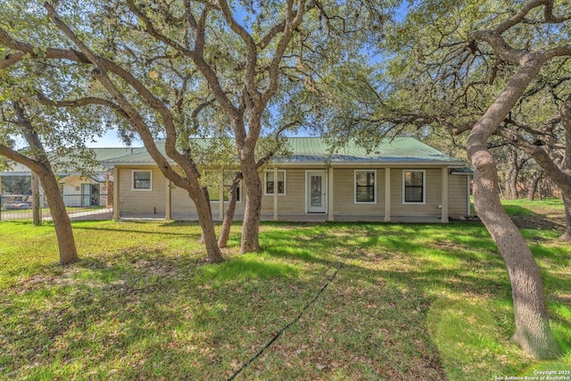 ranch-style house featuring a front yard, metal roof, and fence