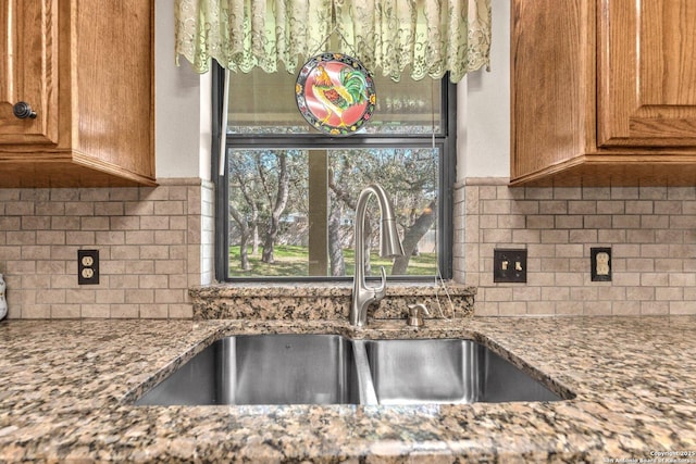 kitchen featuring tasteful backsplash, stone countertops, a sink, and brown cabinets