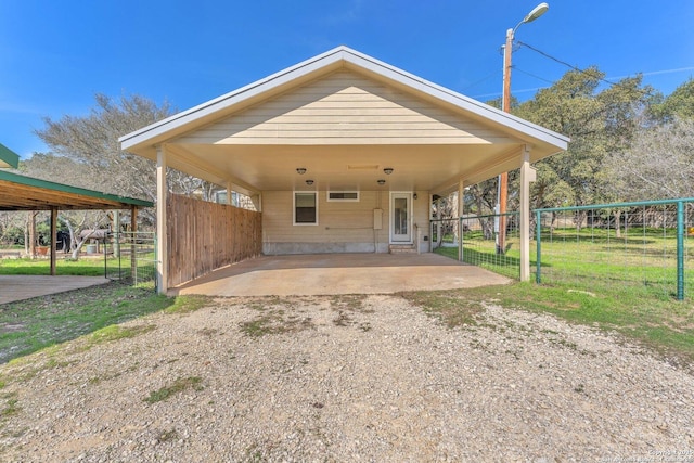 exterior space with an attached carport, fence, and dirt driveway