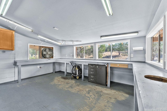 kitchen featuring light countertops, brown cabinetry, a wealth of natural light, and unfinished concrete floors