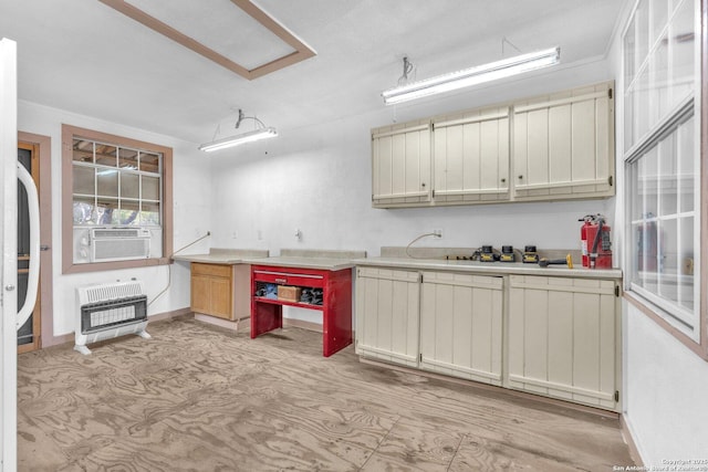 kitchen featuring cream cabinets, cooling unit, baseboards, light countertops, and heating unit