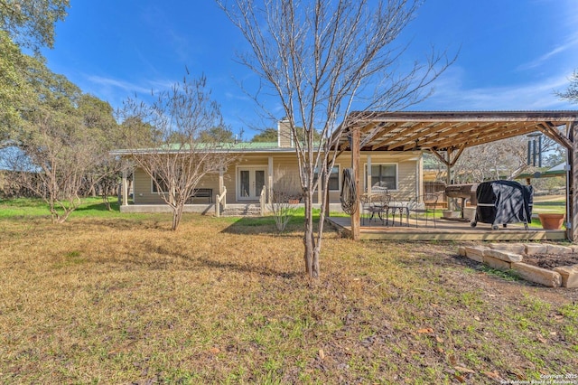 rear view of property featuring a deck, a yard, a chimney, and a pergola