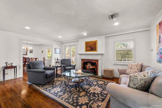 living area featuring visible vents, ornamental molding, wood finished floors, a brick fireplace, and recessed lighting