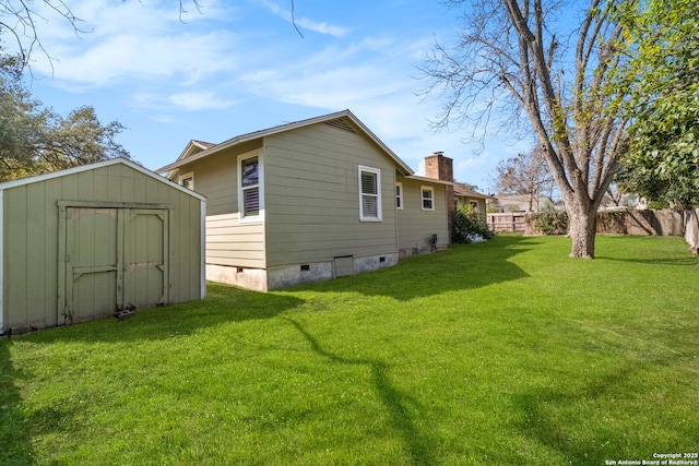 back of house featuring a storage shed, a chimney, crawl space, a yard, and an outdoor structure