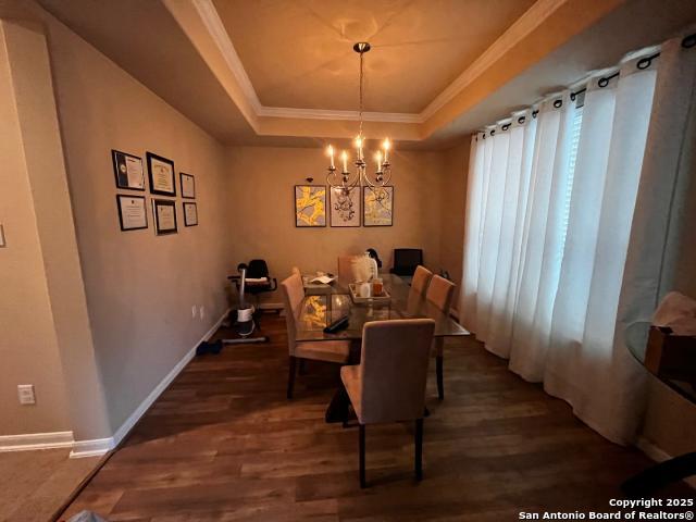 dining room featuring crown molding, a tray ceiling, a chandelier, and dark wood finished floors