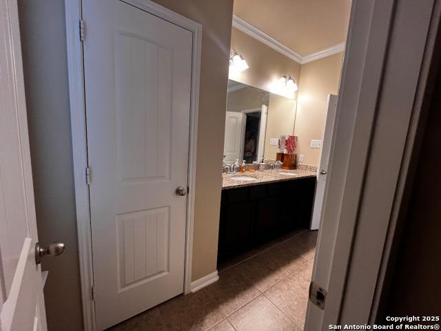 bathroom with ornamental molding, tile patterned floors, a sink, and double vanity