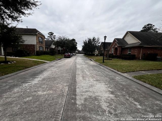 view of street featuring street lights, a residential view, and curbs