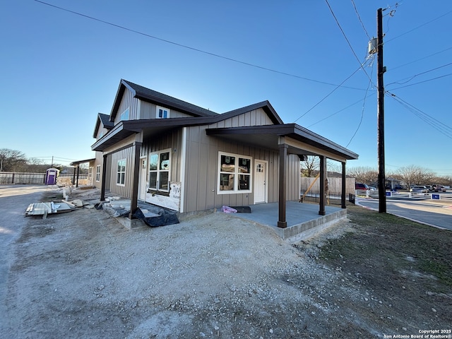 exterior space featuring board and batten siding, a patio area, and fence