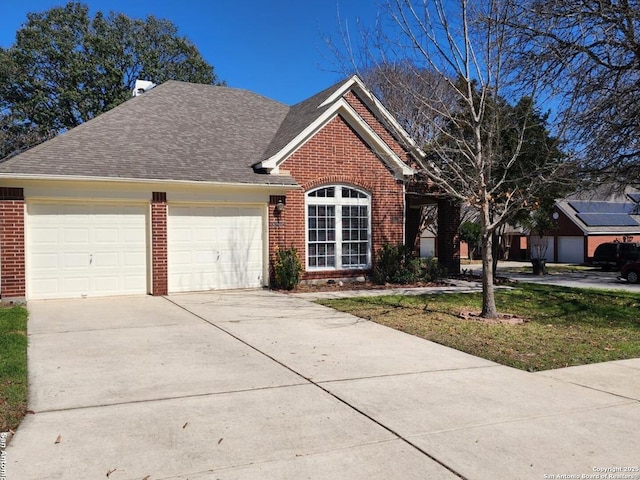 view of front of home featuring an attached garage, a shingled roof, concrete driveway, and brick siding