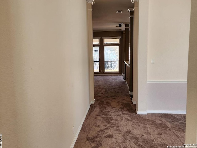 hall with dark colored carpet and baseboards