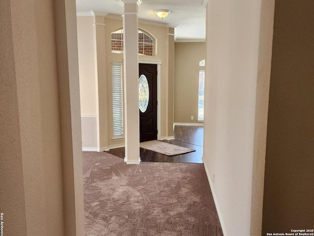 entrance foyer with carpet floors, ornate columns, baseboards, and ornamental molding