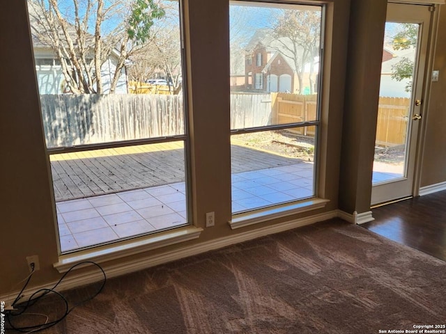 doorway to outside featuring baseboards and dark colored carpet