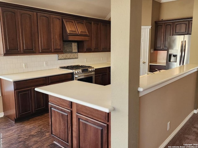 kitchen with tasteful backsplash, light countertops, appliances with stainless steel finishes, dark brown cabinetry, and premium range hood